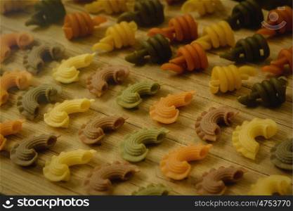 Colorful pasta with nice shapes lined up on wooden board
