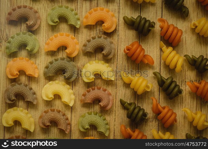Colorful pasta with nice shapes lined up on wooden board