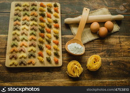 Colorful pasta with nice shapes lined up on wooden board