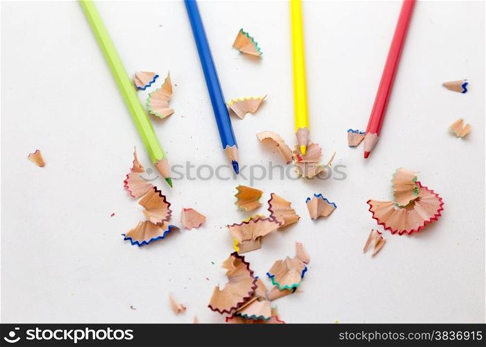 Colorful pencil crayons on white desktop with pencil shavings