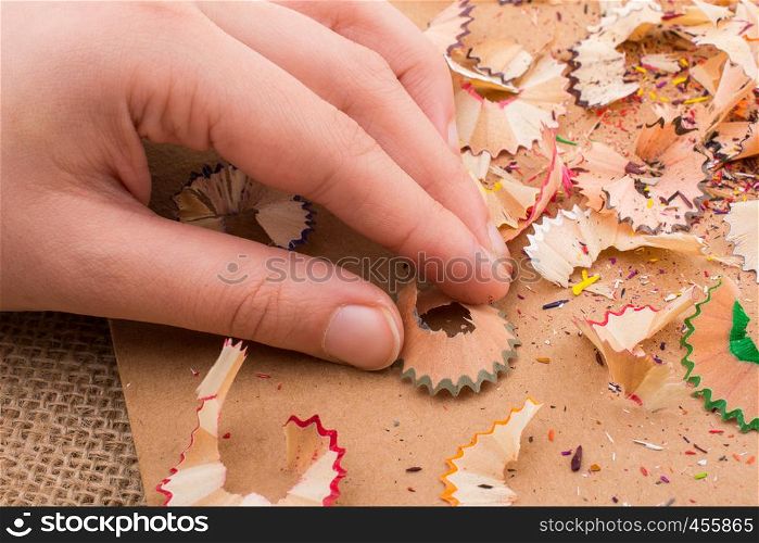 Colorful pencil shavings in hand on a notebook