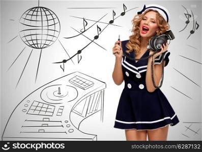 Colorful photo of a clubbing fashionable pin-up sailor girl at the nightclub with big vintage unplugged music headphones on grey sketchy background of a DJ mixer and disco ball.