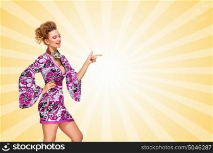 Colorful photo of a fashionable hippie homemaker with vintage music headphones around her neck, pointing aside with her finger on colorful abstract cartoon style background.