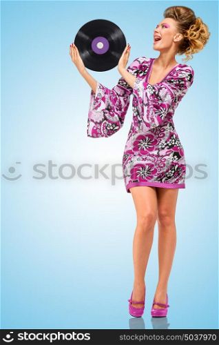 Colorful photo of a happy fashionable hippie homemaker with a retro vinyl record in her hands on blue background.