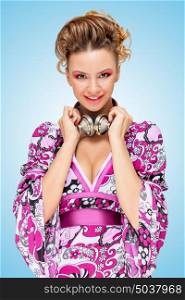 Colorful photo of a smiling fashionable hippie homemaker with metal vintage music headphones around her neck on blue background.