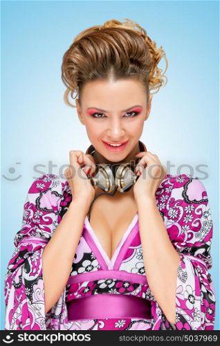 Colorful photo of a smiling fashionable hippie homemaker with metal vintage music headphones around her neck on blue background.