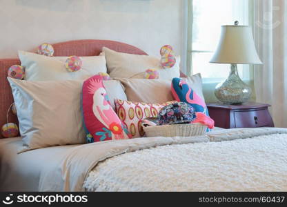 colorful pillows and bedside table lamp in modern kid bedroom interior