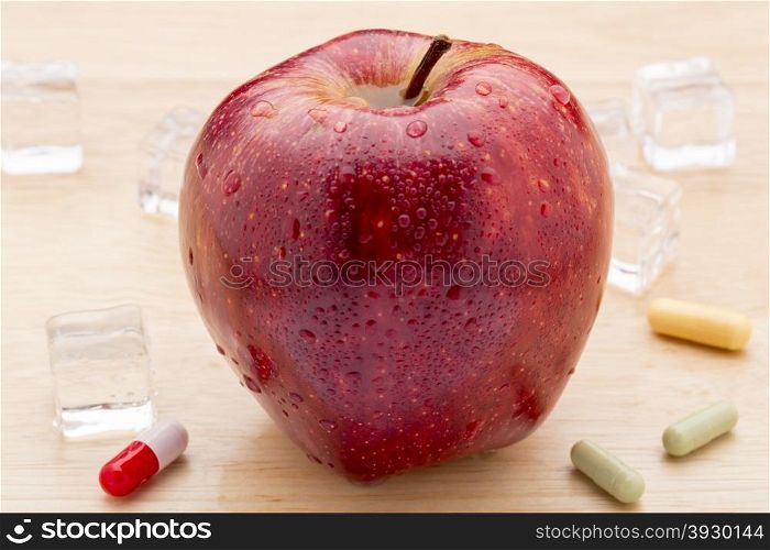 Colorful pills and red apple. Colorful pills and freshest red apple on wooden background