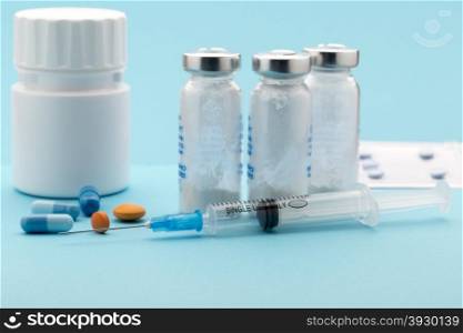 Colorful pills bottle and injection syringe. Colorful pills bottle and injection syringe on blue background