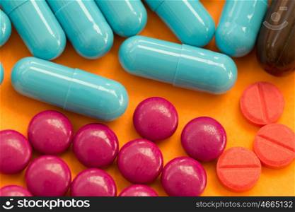 Colorful pills on orange background. Medicines to heal