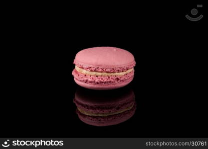 Colorful pink macaroon over a black background