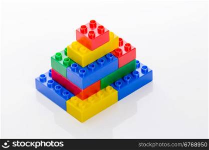 Colorful plastic building bricks forming building on white background