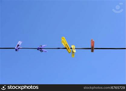 Colorful plastic clothespins on a background of blue sky