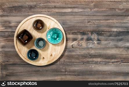 Colorful plates and board on wooden background. Kitchen utensils