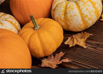 Colorful pumpkins and dry maple leaves frame on wooden background , autumn harvest , Halloween or Thanksgiving concept. Pumpkins and maple leaves