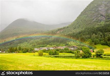 Colorful rainbow over the fields, lake and houses of Skei village, Jolster in Sogn og Fjordane county, Norway.