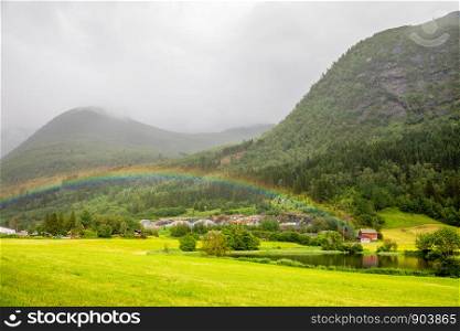 Colorful rainbow over the fields, lake and houses of Skei village, Jolster in Sogn og Fjordane county, Norway.