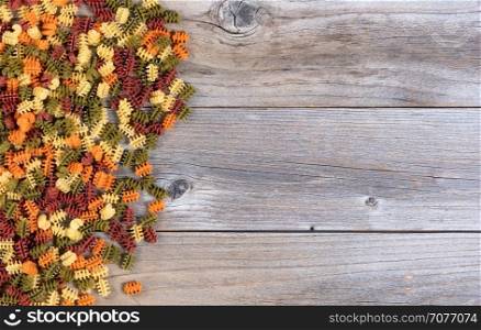 Colorful raw twisted pasta on rustic wood background with copy space available
