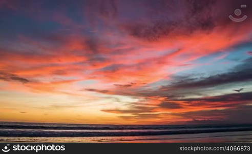 Colorful red sunset at ocean with big waves