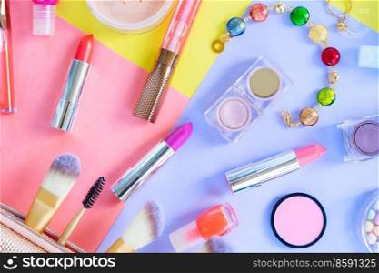 Colorful scattered make up products close up on plain color block background. Colorful make up flat lay scene