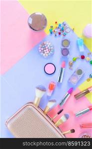 Colorful scattered make up products on plain color block background. Colorful make up flat lay scene