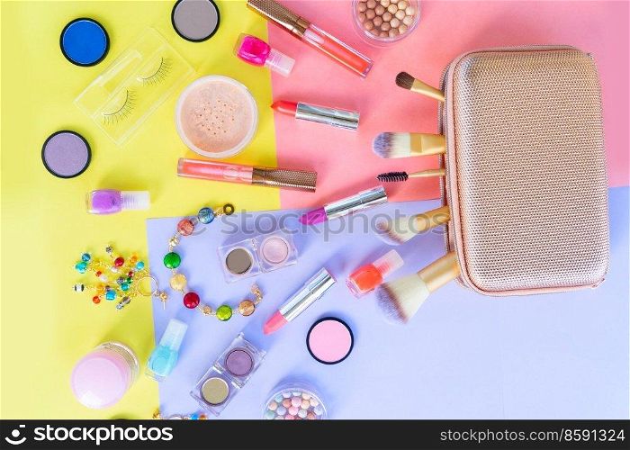 Colorful scattered make up products with golden pursue on plain color block background. Colorful make up flat lay scene