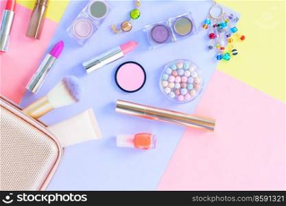 Colorful scattered make up products with pursue on plain color block background. Colorful make up flat lay scene