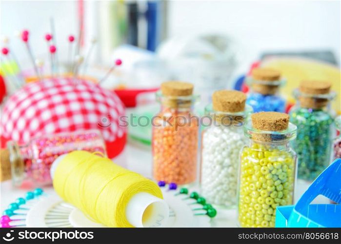 Colorful seed beads, thread, pins and other accessories for needlework close-up