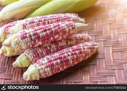 Colorful small ears waxy corns with silk, corn leaf on bamboo weave background for food and drink design.