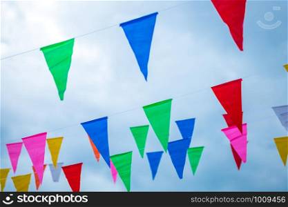 Colorful small flags paper made hanging on the rope with blue sky background, selective focus.