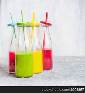 Colorful smoothies assortment in bottles with drinking Straws: green,yellow,red, front view