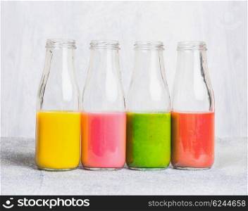Colorful smoothies assortment in glass bottles on light table, side view. Superfoods and health or detox diet food concept.