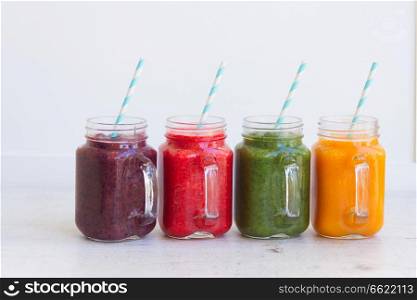 Colorful smoothy drinks in glass jars on white table. Fresh smoothy drink