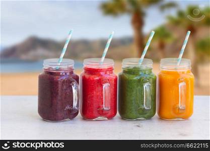 Colorful smoothy drinks in glass jars on white table. Fresh smoothy drink