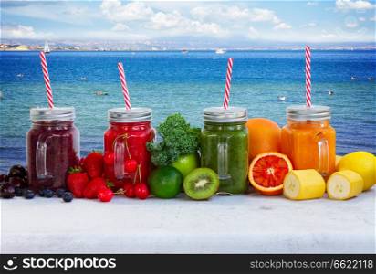 Colorful smoothy drinks in glass jars with igredients by seaside. Fresh smoothy drink with igredients