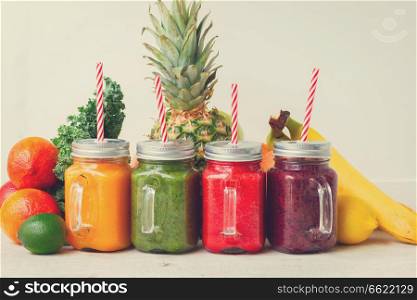 Colorful smoothy drinks in glass jars with straws and igredients, retro toned. Fresh smoothy drink with igredients