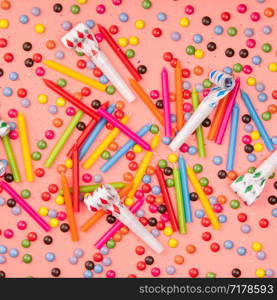 Colorful sprinkles, blowers and birthday candles on pink background, flat lay, top view. Colorful sprinkles, blowers and birthday candles on pink background