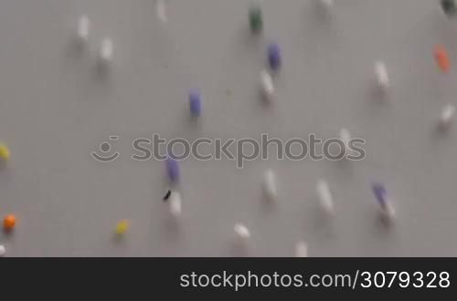 Colorful sprinkles sugar candy moving on white surface background