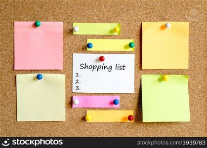 Colorful sticky notes on cork board background and text concept shopping list