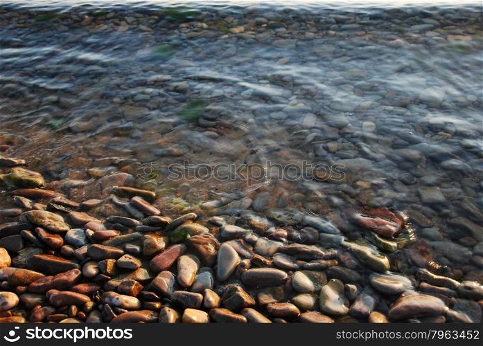 Colorful stones and pebbles at the waters edge by coastline