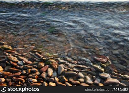 Colorful stones and pebbles at the waters edge by coastline