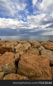 Colorful stones on a shore with fluffy clouds at the horizon. Vertical view