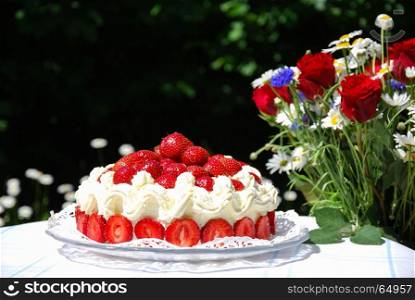 Colorful strawberry cake and a bouquet with summer flowers