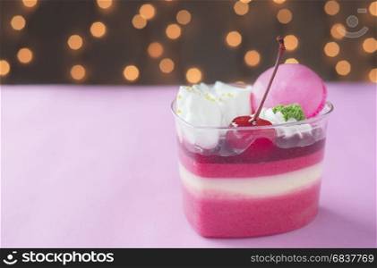 Colorful strawberry cake and macaron over shiny bokeh background
