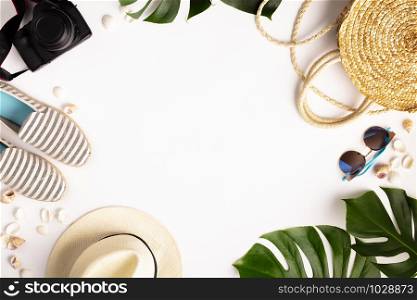 Colorful summer female fashion outfit flat-lay. Straw hat, camera, bag, summer shoes, sunglasses, shells and tropical leaves over white background, top view. Summer fashion, holiday concept, space for text