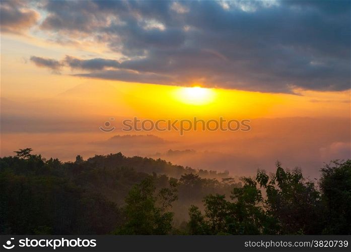 Colorful sunrise over jungle with Merapi volcano behind and Borobudur temple, Indoneisa