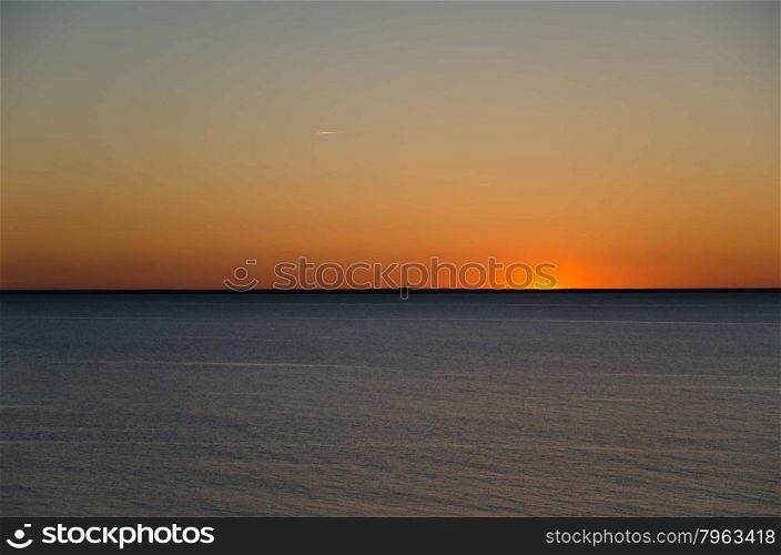 Colorful sunset at the horizon by calm water
