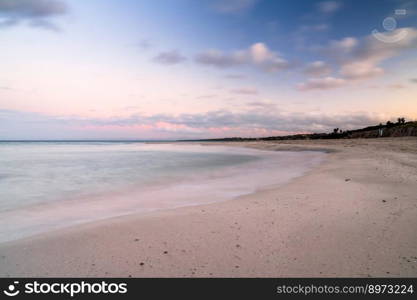 Colorful sunset over the picturesque white sand beach and turquoise waters at La Pelosa Beach