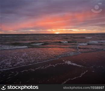 colorful sunset with reflections in pools on beach of normandy in france