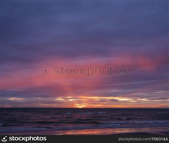 colorful sunset with reflections in pools on beach of normandy in france